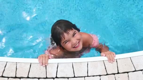 Kız çocuğu yazın mavi havuzda yüzer. — Stok video