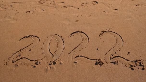 Das Meer auf dem Sand am Strand spült die Zahlen von 2022 als Konzept des scheidenden Jahres weg — Stockvideo