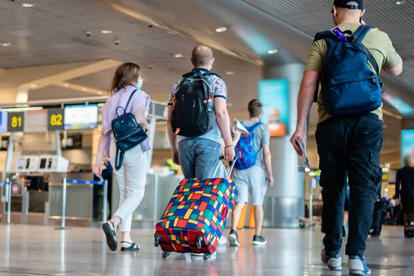 Personas con máscaras médicas caminando con maletas maletas en el concepto de viaje del aeropuerto — Foto de Stock