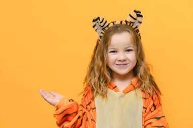 Kaplan kostümlü sevimli kız izole edilmiş sarı arka planda ve kısa noel konsepti için yeri var.