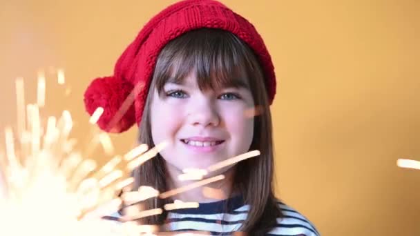 Glad flicka barn i Santa hatt med tomtebloss på isolerad gul bakgrund jul koncept — Stockvideo
