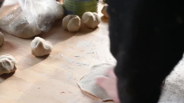 Mężczyzna w kuchni w domu przygotowuje pastie na stole, wywala ciasto, wkłada mielone mięso do domu — Wideo stockowe