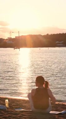 dikey video. Bir adam lotus pozisyonunda oturur. Sahilde gün batımında. izoterik tema