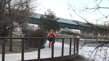 Turuncu üniformalı erkek işçi, özel aletlerle şehirdeki karları temizliyor.
