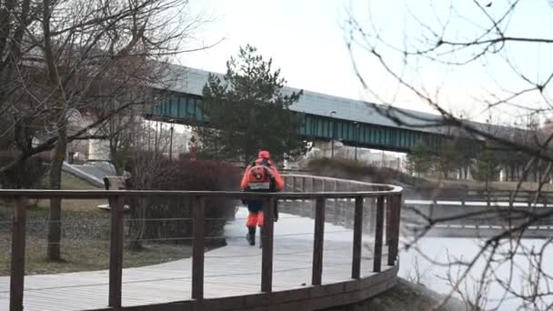 Mannelijke werknemer in oranje uniform verwijdert sneeuw op de straat met speciale gereedschappen — Stockvideo