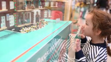 27,11,2021 Rus Moskova 'lı bir kız bir alışveriş merkezinde bir Lego inşaatçısıyla bir gösterinin önünde duruyor.