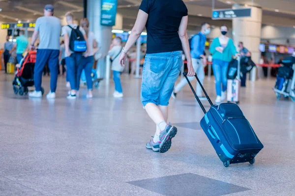 Personas con máscaras médicas caminando con maletas maletas en el concepto de viaje del aeropuerto — Foto de Stock