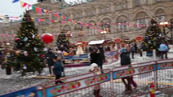 09,12,2021 09,12,2021 Russie Moscou Les gens marchent sur la Place Rouge dans le contexte du marché de Noël et du carrousel en hiver — Video