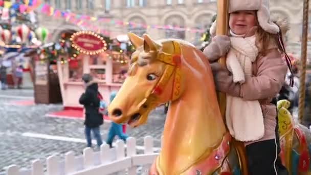 09,12,2021 Rosja Moskwa mała dziewczynka dziecko jeździ na koniu na karuzeli na czerwonym placu w Moskwie zimą — Wideo stockowe
