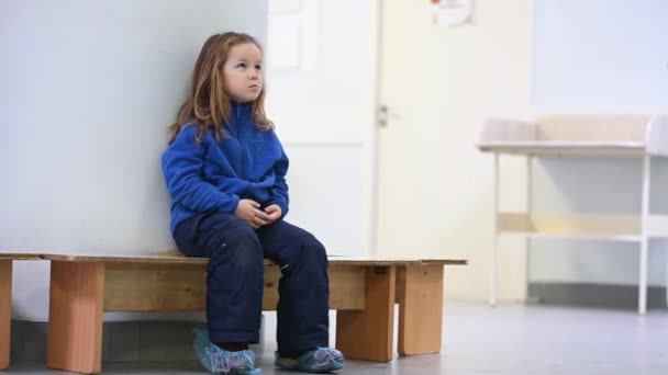 Маленькая забавная девочка играет в клинике ожидая встречи с врачом — стоковое видео
