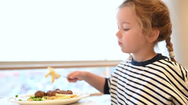 Meisje, kind eten frietjes, fast food in een restaurant in een winkelcentrum — Stockvideo