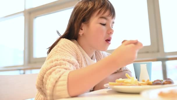 Κορίτσι, παιδί τρώει πατάτες, fast food σε ένα εστιατόριο σε ένα εμπορικό κέντρο — Αρχείο Βίντεο