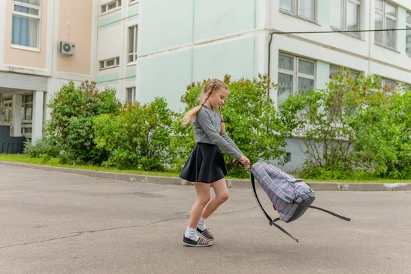 Söta glada flicka skolflickor med ryggsäckar spelar nära skolan — Stockfoto