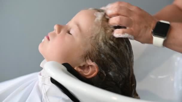 Милая девочка ребенок получает стрижку в салоне мыть волосы — стоковое видео