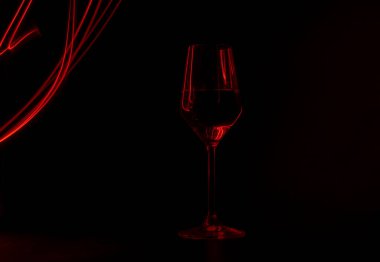 Siyah arka planda kırmızı ışık boyasıyla aydınlatılmış şampanya bardağı.
