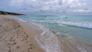 Turkuaz deniz ve bulutlu gökyüzü ile sahil kıyısı