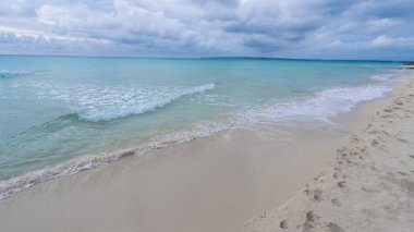 Turkuaz deniz ve bulutlu gökyüzü ile sahil kıyısı