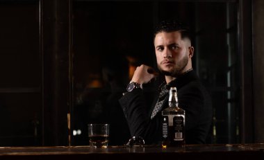 Barda bir bardak viskisi olan zarif bir adam.