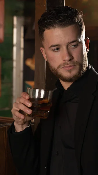 elegant man with glass of whiskey at a pub bar