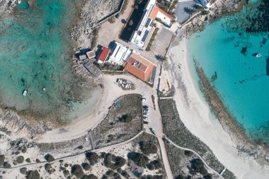 İnsansız hava aracından görünen turkuaz denizle çevrili bir adanın tepesinde.