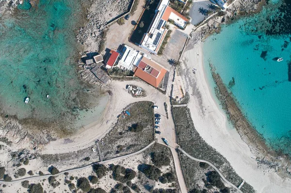 İnsansız hava aracından görünen turkuaz denizle çevrili bir adanın tepesinde.