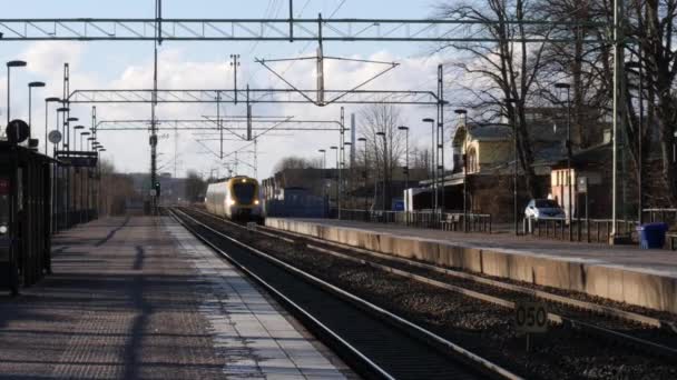Vlak přijíždí na prázdnou nástupiště v malém městě ve Švédsku, pomalý pohyb — Stock video