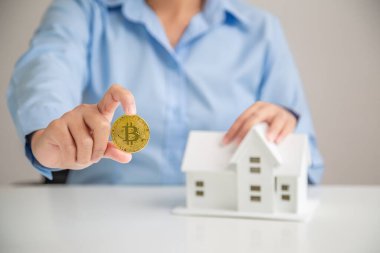 Tasarruf evi, Yatırım Evi Bitcoin almak için elinde Bitcoin tutan kadın. Ev satın alma tasarruf kavramı.