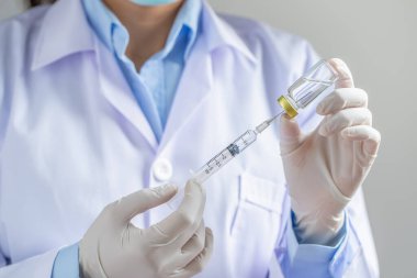 Doktor ya da bilim adamı bir şırıngayı sıvı aşılarla dolu bir şırıngayla laboratuarda dolduruyor. Aşı ve bağışıklık. Kapat..