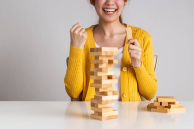 Mutlu Asyalı kadın ahşap blok kulesine tahta bloğu yerleştirip çekiyor..