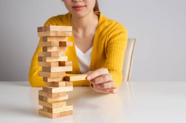 Asyalı kadın tahta blok kule oyununa tahta blok yerleştiriyor ve çekiyor..