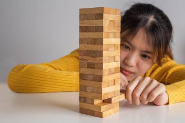 Asyalı kadın tahta blok kule oyununda tahta bloğu çekiyor..