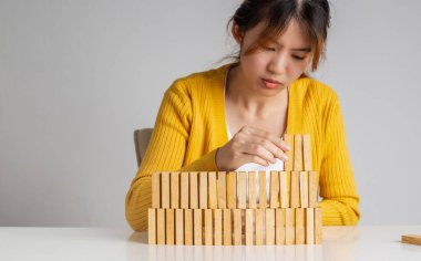 Asyalı kadın ahşap bloklardan bir duvar inşa ediyor.