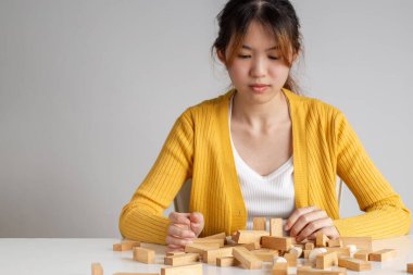 Asyalı kadın tahta blok kule oyununda tahta blok oynuyor..
