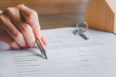 Kira sözleşmesi belge konsepti. Emlakçı ya da komisyoncu kiracının belgelerini kalem ve anahtarla, kira sözleşmesi formuyla, imza el, anlaşma ile imzalarken gösterir.