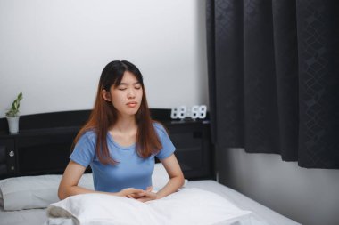 Asyalı kadın yatakta meditasyon yapıyor, sağlıklı bir yaşam tarzı..