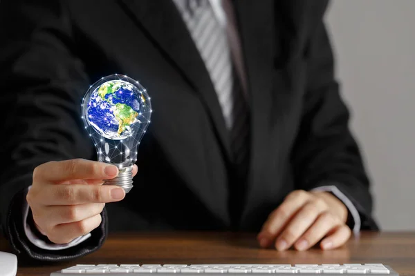 Businessman hand hold light bulb with globe inside. Concept of doing business with care for environment and saving the world. Elements of this image furnished by NASA.