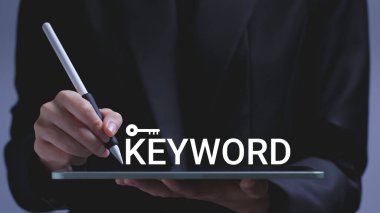 Businessman hand pointing pen at tablet screen with word keyword. SEO search ranking concept.