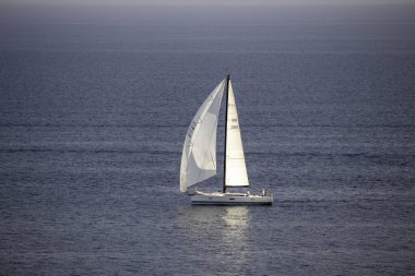 Güneşli bir günde, mavi denizde beyaz bir tekne dinleniyor.