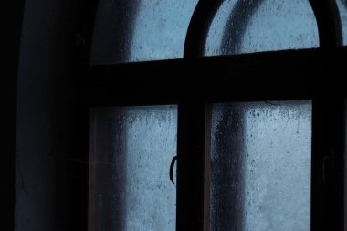 Alacakaranlıktaki eski pencere, örümcek ağında, kışın donmuş cam.