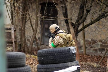 Hava yumuşaklığı oyunu, üniformalı ve kasklı bir oyuncu, hava yumuşaklığında bir silahla, özel bir oyun alanında, eski tekerlerden korunaklı sığınaklar.