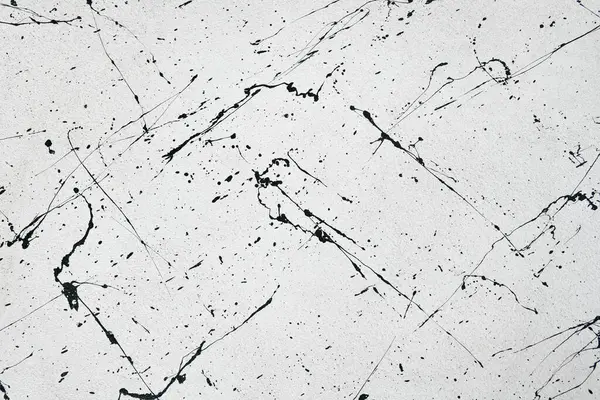 Beyaz beton duvar yüzeyine siyah suluboya sıçramış.