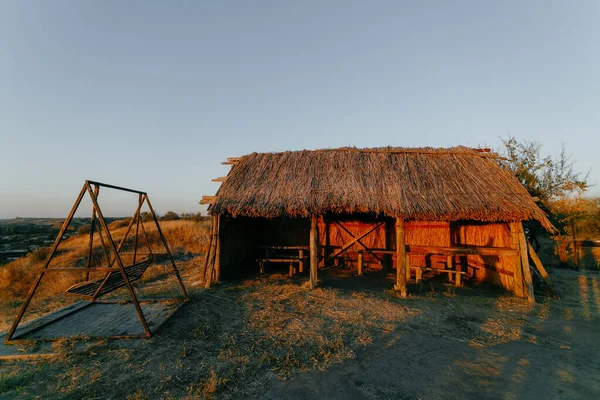 Cabaña de lengüeta y viejo columpio metálico en la puesta del sol —  Fotos de Stock