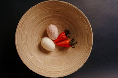 Tatlı örülmüş yumurta ve havuç oyuncakları bambu tabağında