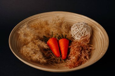 Paskalya dekoru. Bambu tabağında örülmüş yumurta, havuç ve pampa.