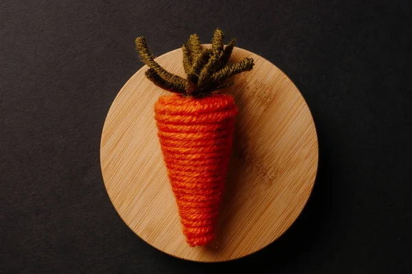 Cute knitted carrot toy on wooden plate — Stock Photo, Image