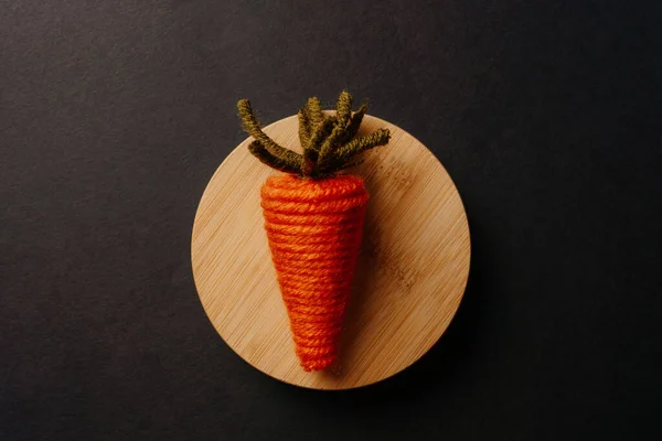 Cute knitted carrot toy on wooden plate — Stock Photo, Image