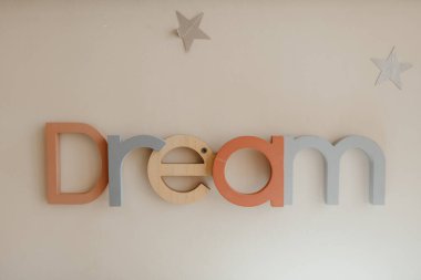 Rüya. Kremalı arka planda ahşap harfler ve yıldızlar asılı.