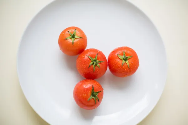 Cuatro tomates en un plato — Foto de Stock