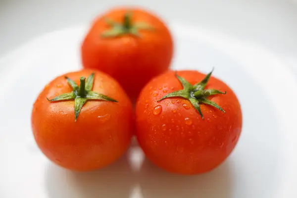 Ripe tomatos on a white plate — Stock Photo, Image