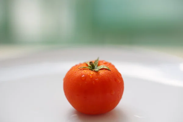 Tomate maduro en un plato blanco — Foto de Stock